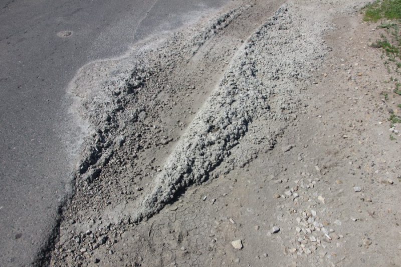 Профилактика трещин. Разлитый бетон на дороге. Вода разлитая на бетоне. Комки разлитого бетона на дороге. Кучки вдоль дороги в Крыму с песком.